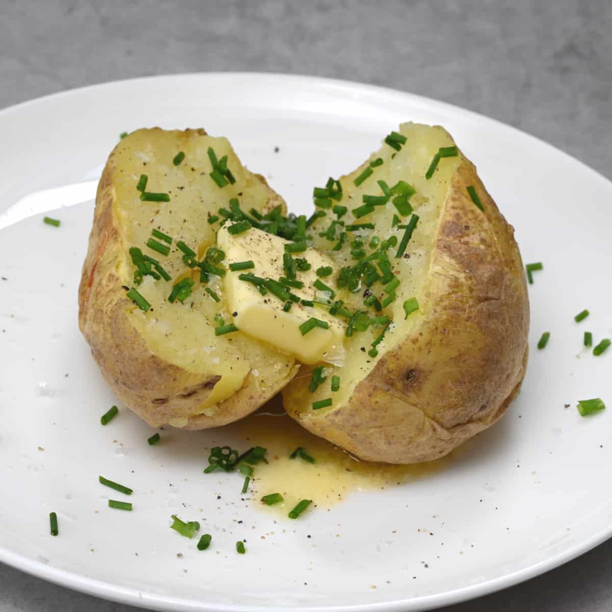 Potato on white plate with chives and melted butter
