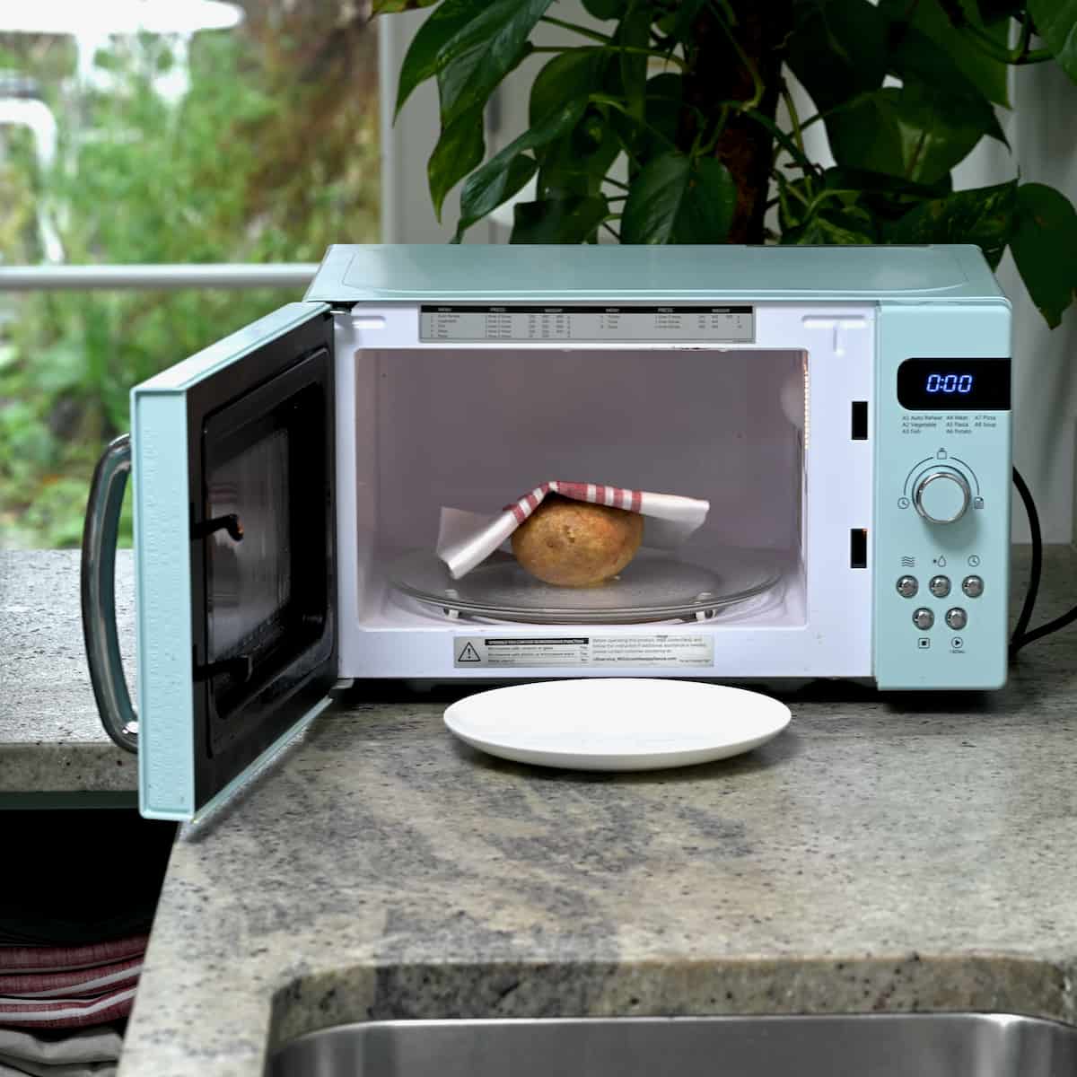 Using a towel remove the baked potato from microwave
