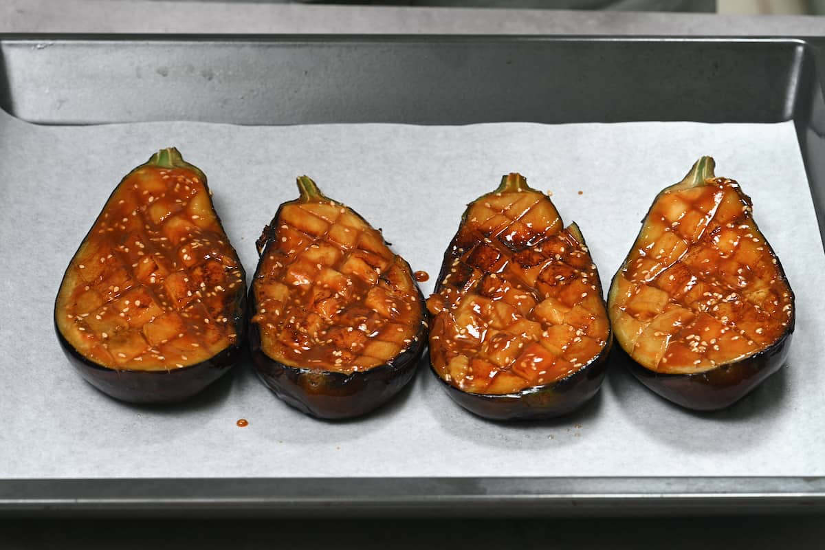 Eggplant coated in miso sauce on oven tray with parchment paper.