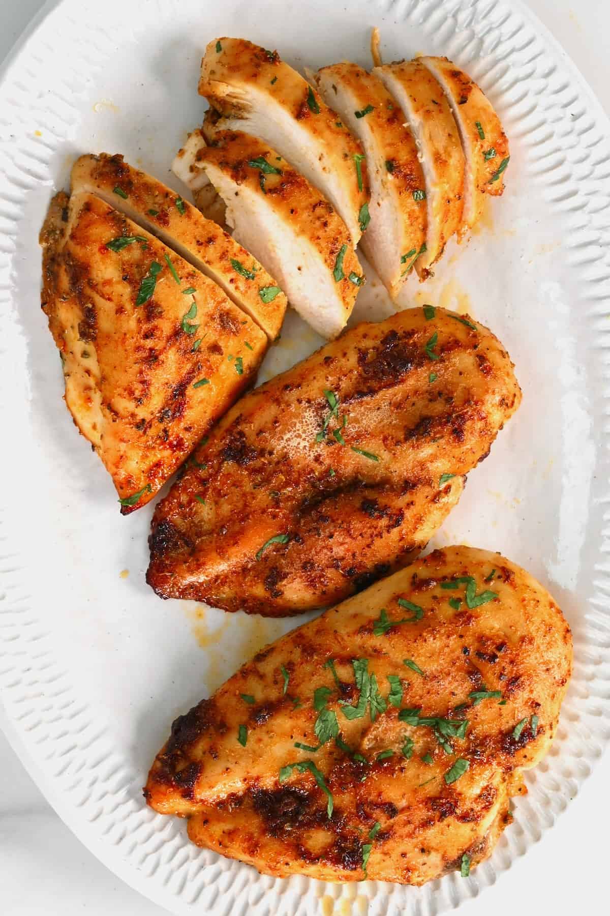 Sliced baked chicken breast topped with parsley