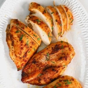 Sliced baked chicken breast topped with parsley