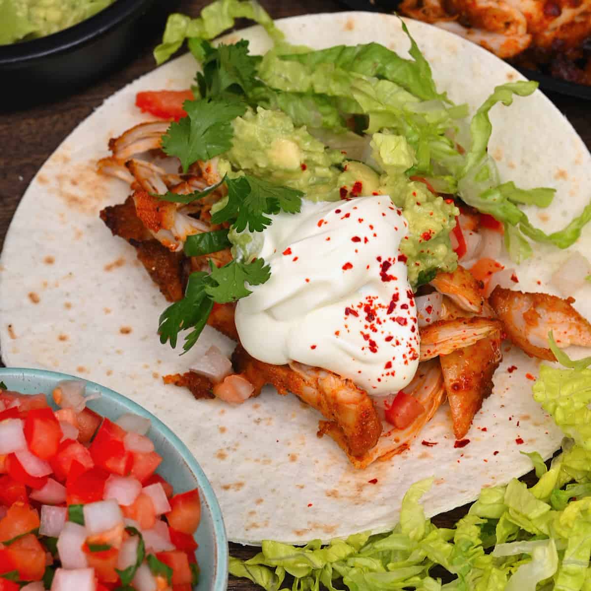 Stacking toppings into tortilla to make chicken tacos