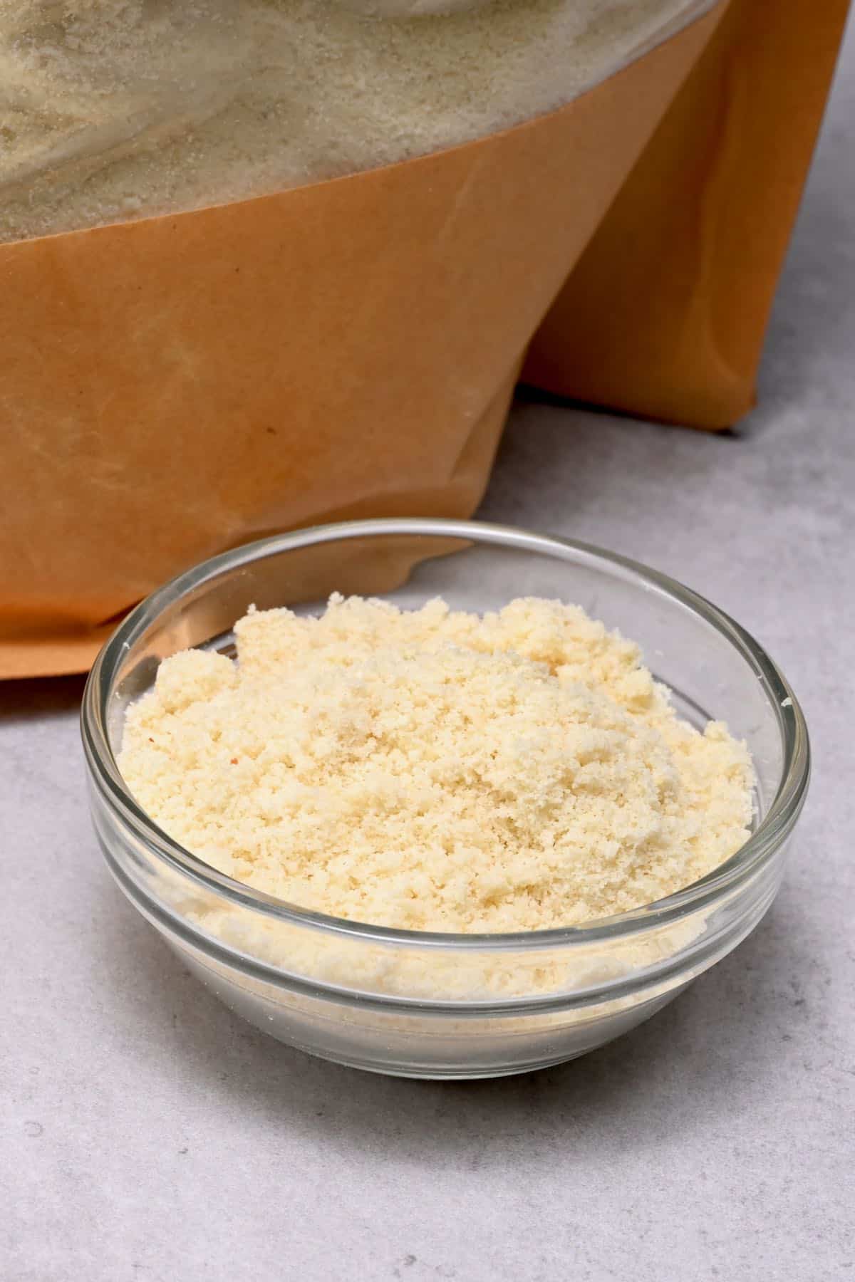 almond flour in a glass bowl with almond flour bag behind
