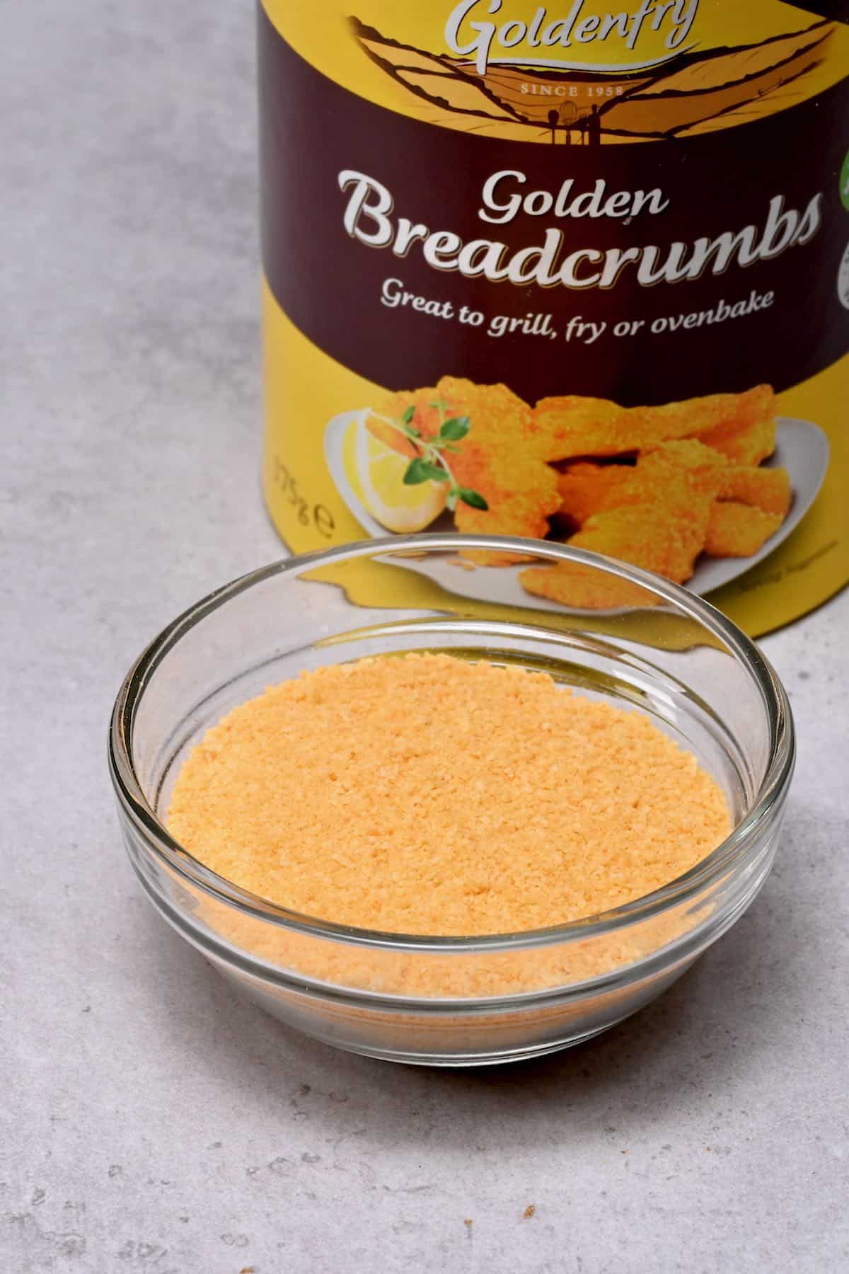 breadcrumbs in a glass bowl with breadcrumbs jar behind
