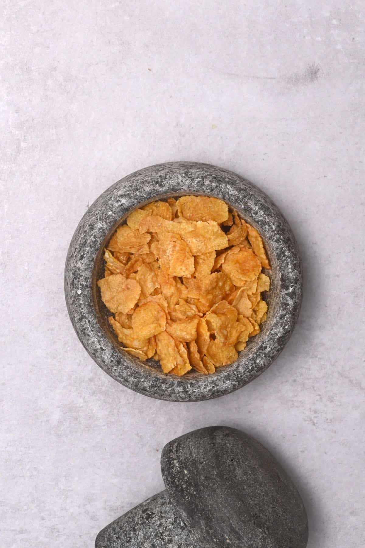 cornflakes inside pestle and mortar next to it