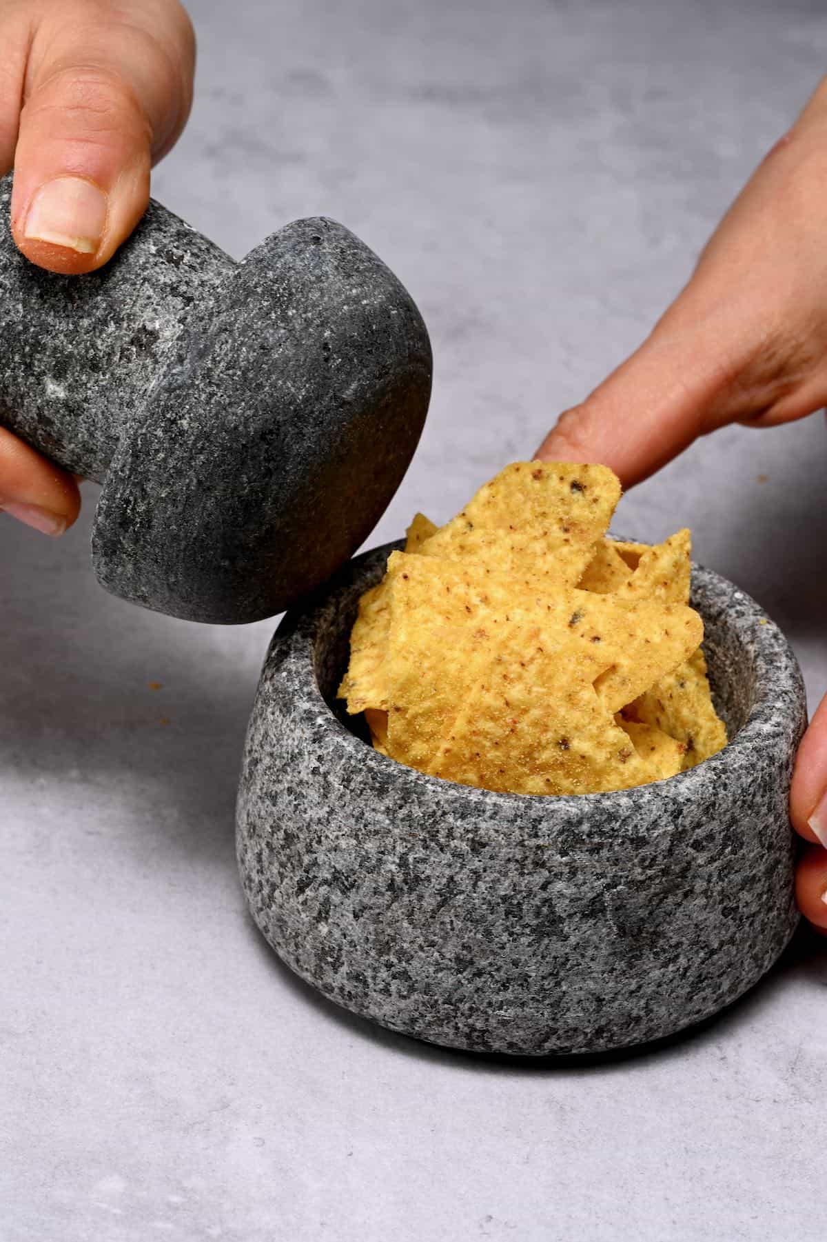 curshing tortilla chips with a mortar