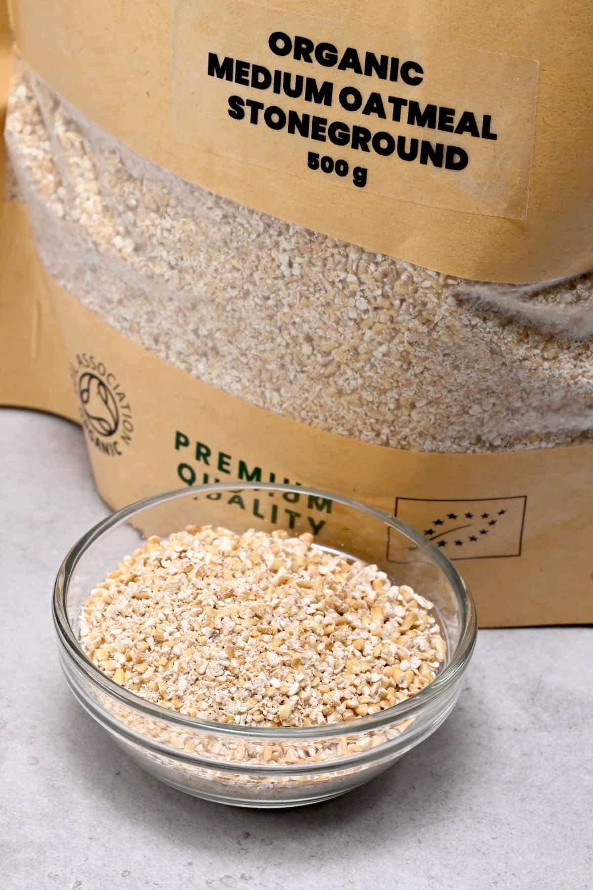 ground oatmeal in a glass bowl with oatmeal bag behind