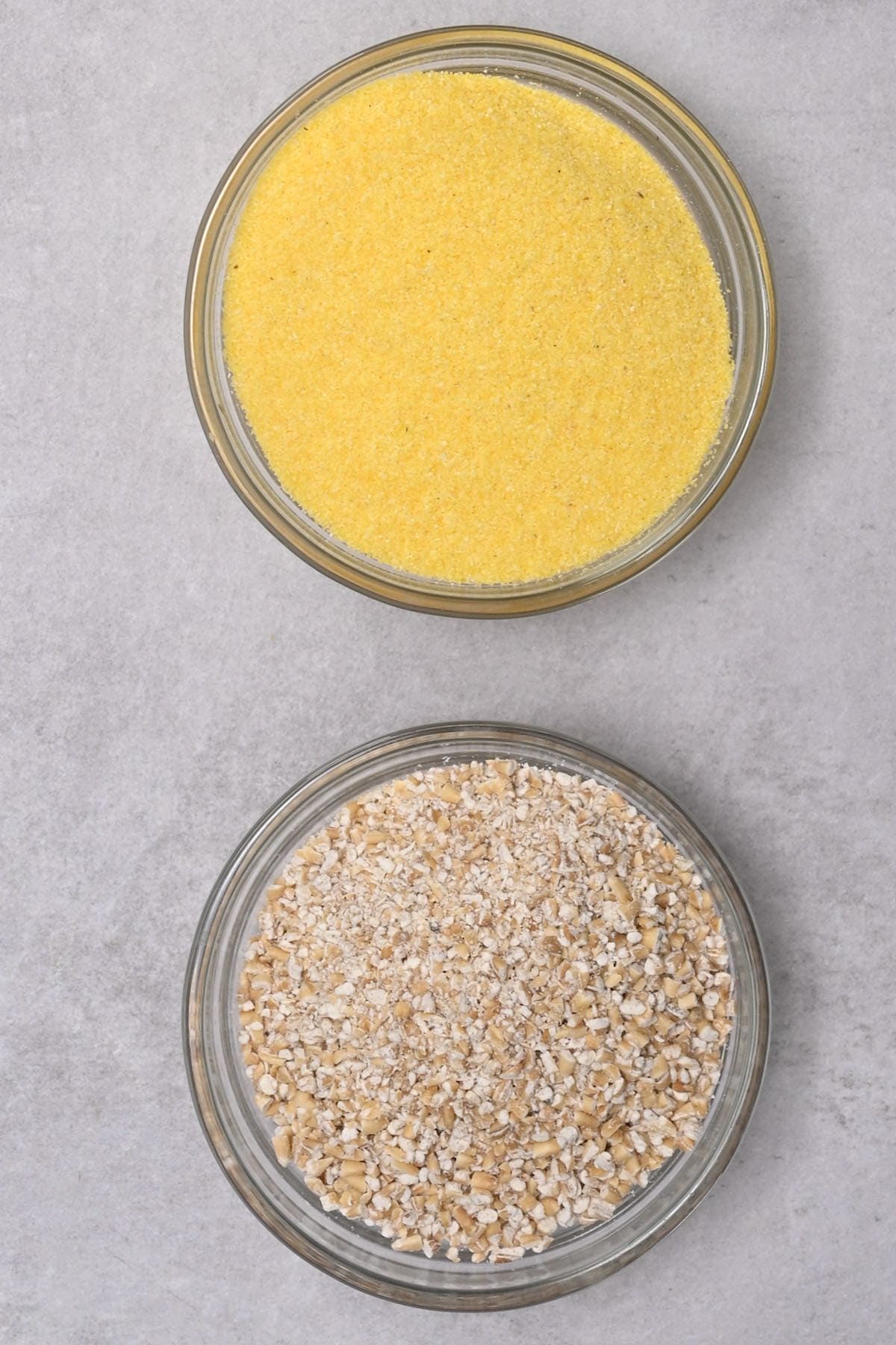 ground oats next to cornmeal in glass bowl