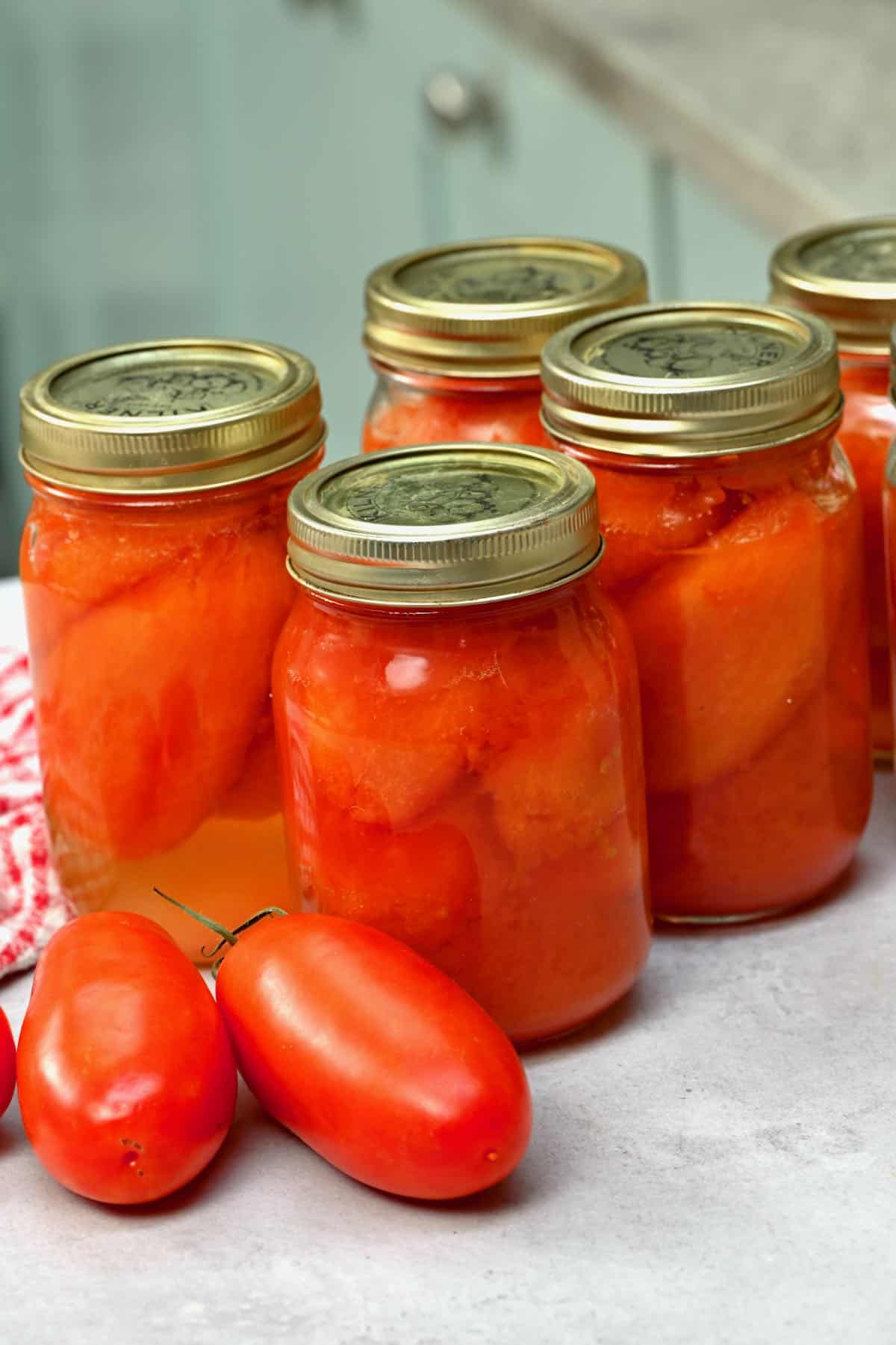 jars of canned whole tomatoes on a grey background