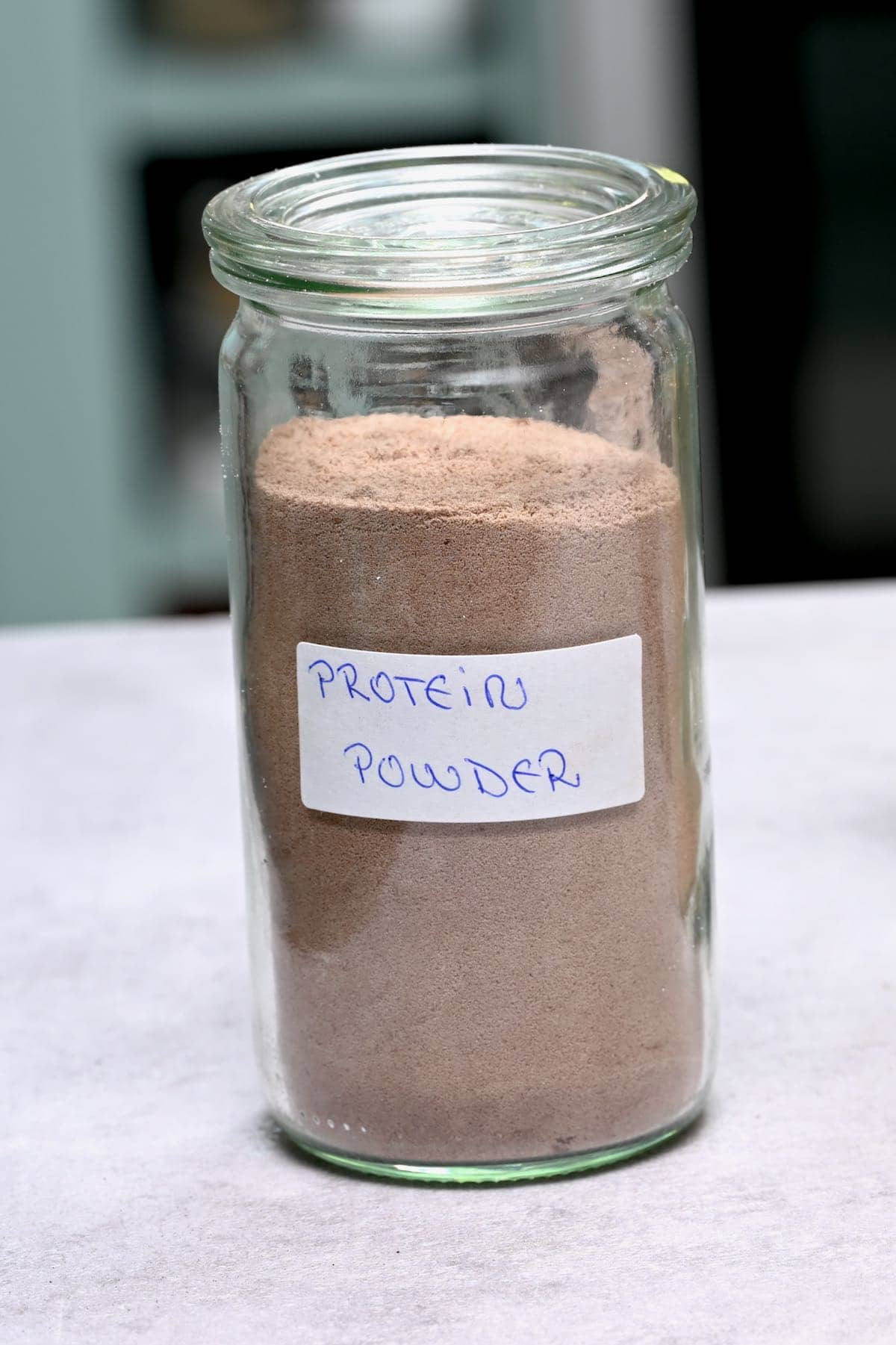 side view of chocolate protein powder in a glass jar