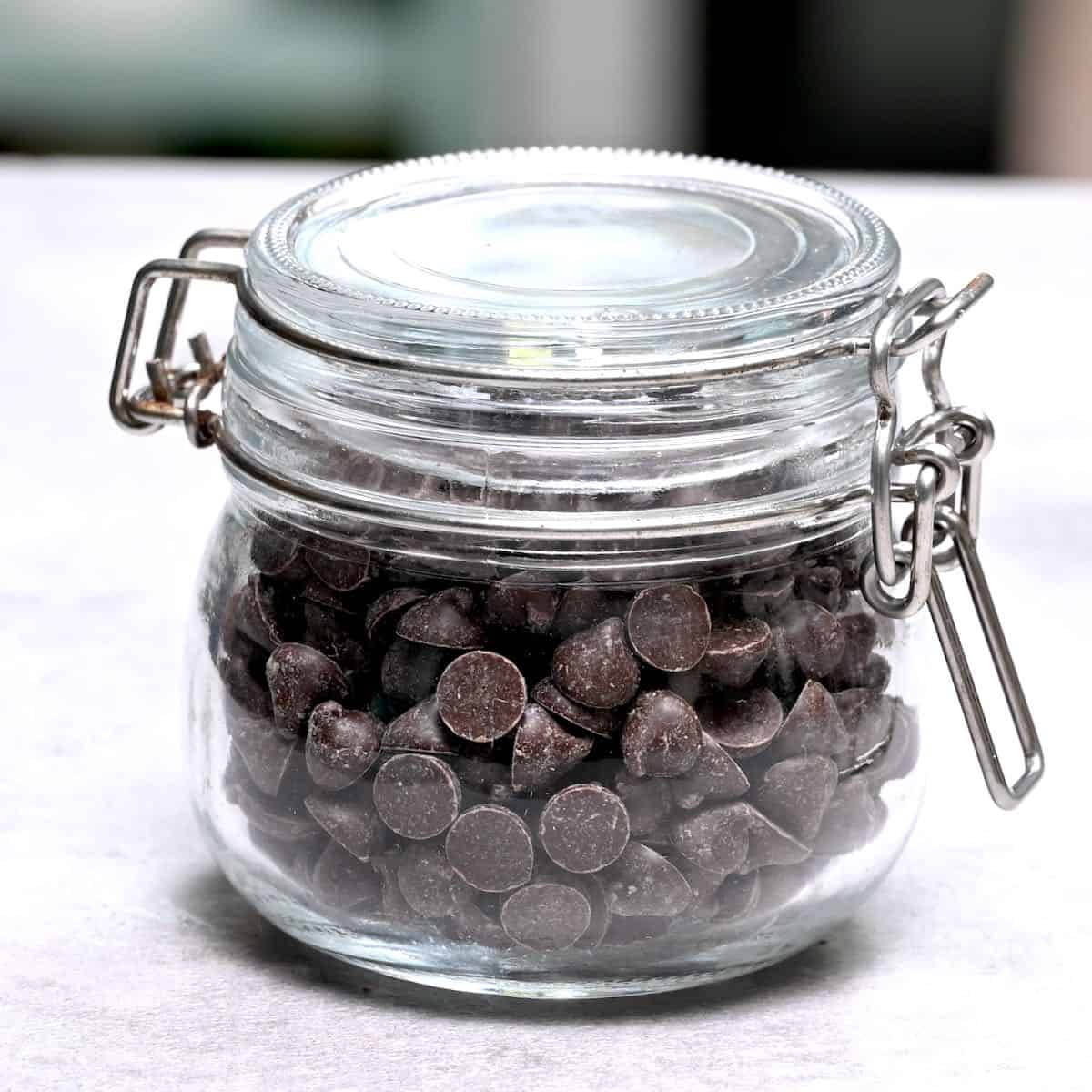 side view of dark chocolate chips in a glass jar