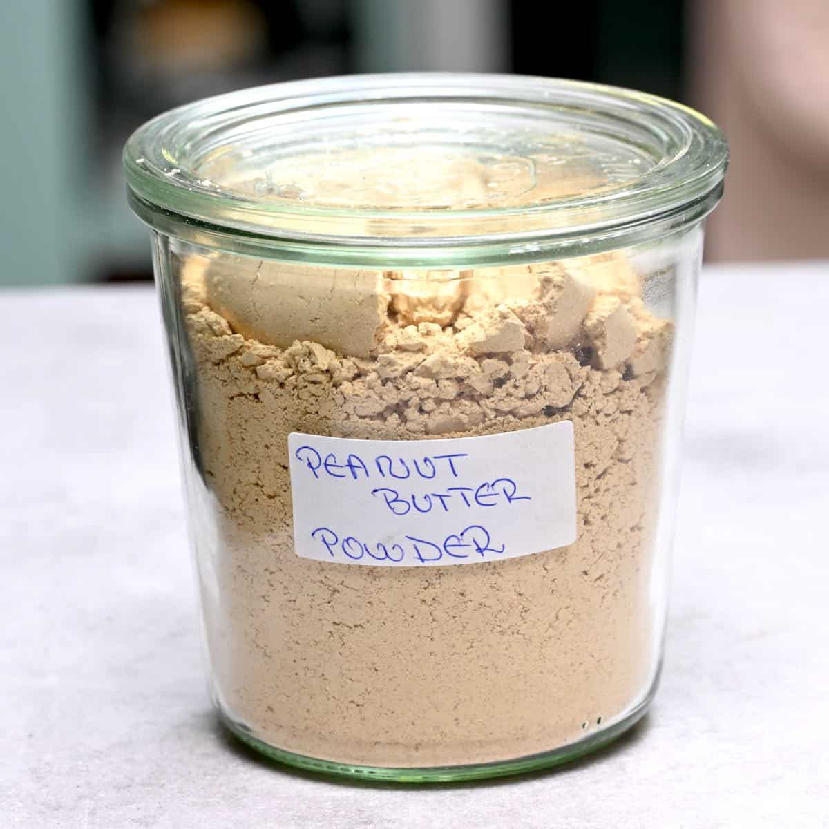 side view of peanut butter powder in a glass jar