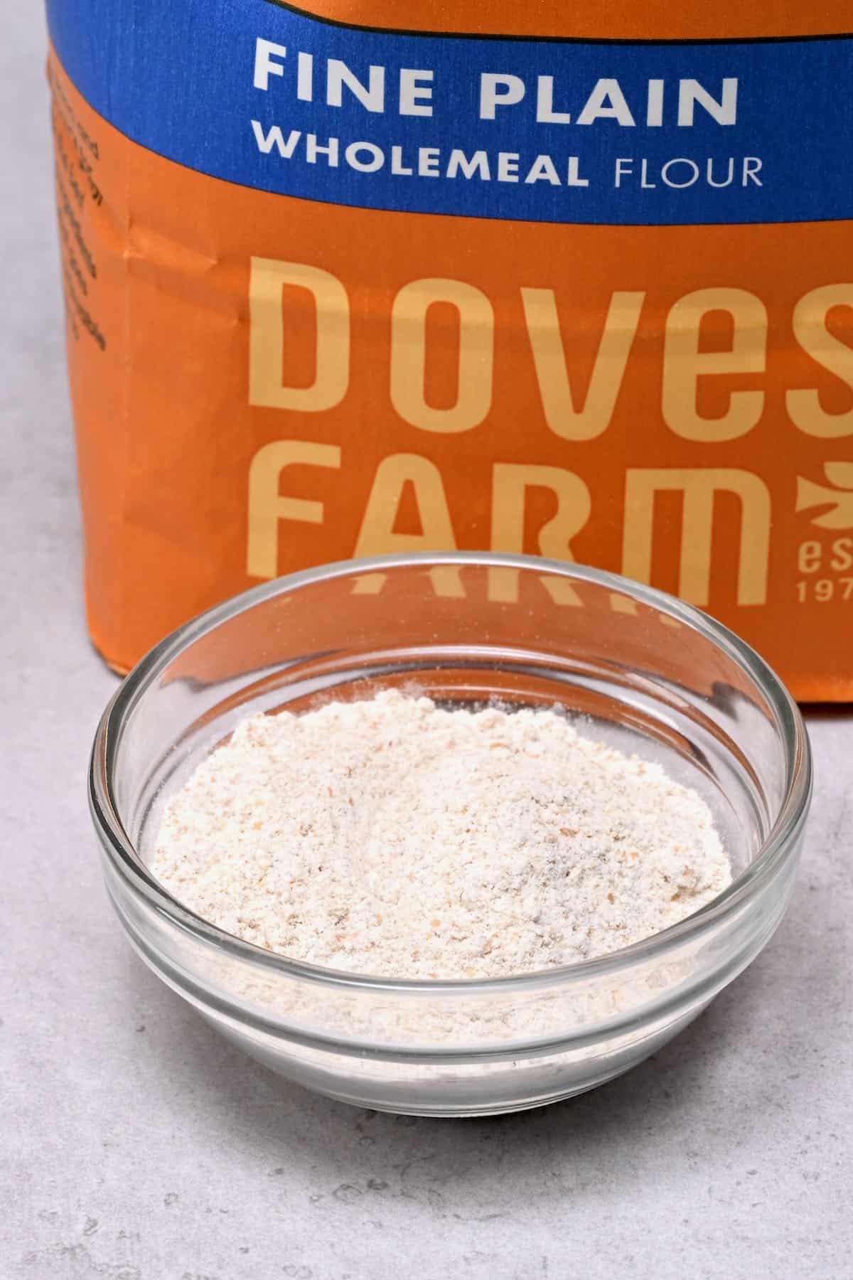 wholemeal flour in a glass bowl with wholemeal flour bag behind