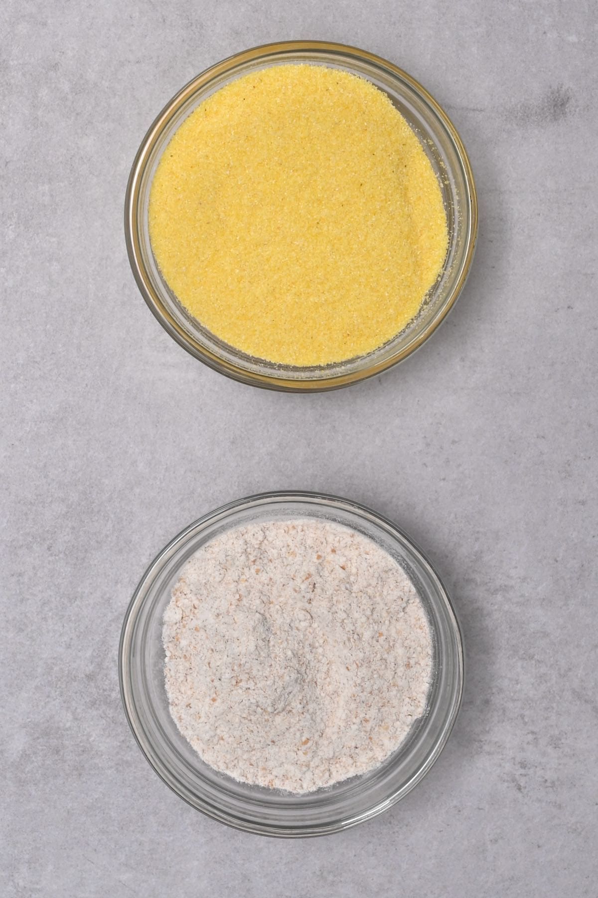 wholemeal flour next to cornmeal in glass bowl