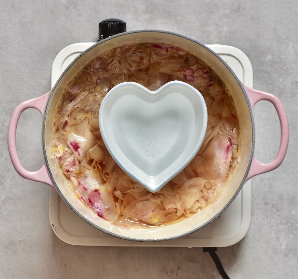 A saucepan with a small bowl filled with distilled rose water