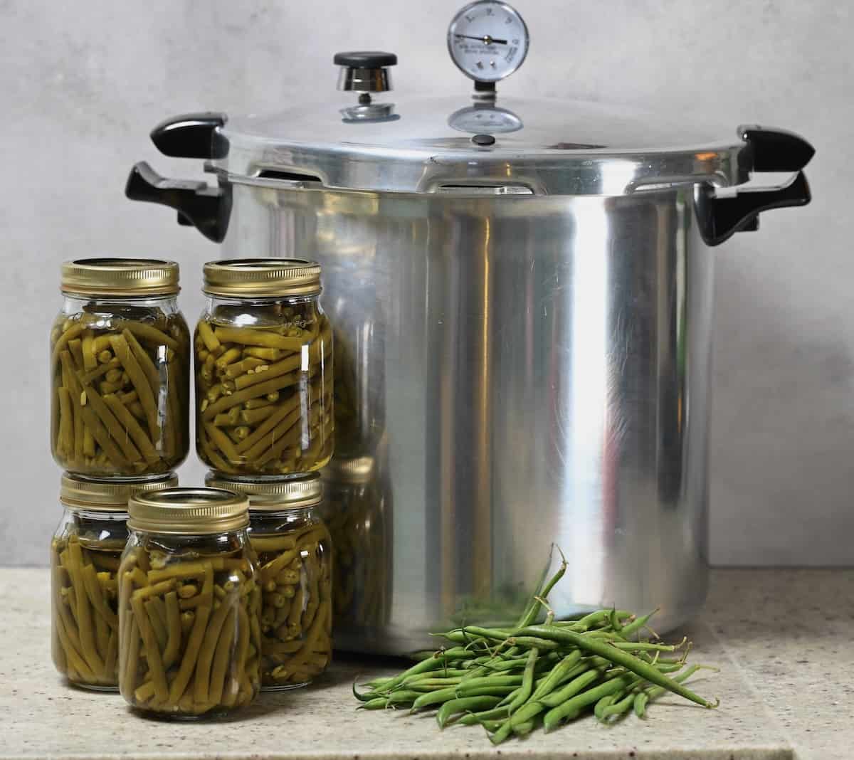 Five jars with green beans canned at home and a large canner