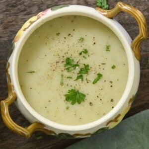 A bowl with homemade potato leek soup topped with a bit of parsley