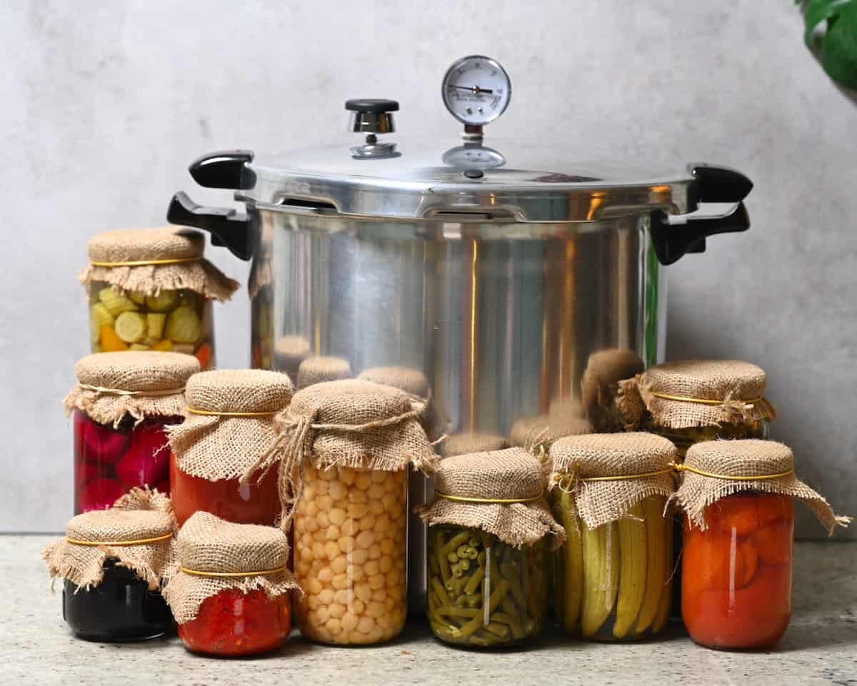 A large pressure canner and several jars with homemade canned food
