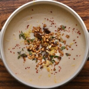 A bowl of cauliflower soup topped with toasted pine nuts and lemon zest