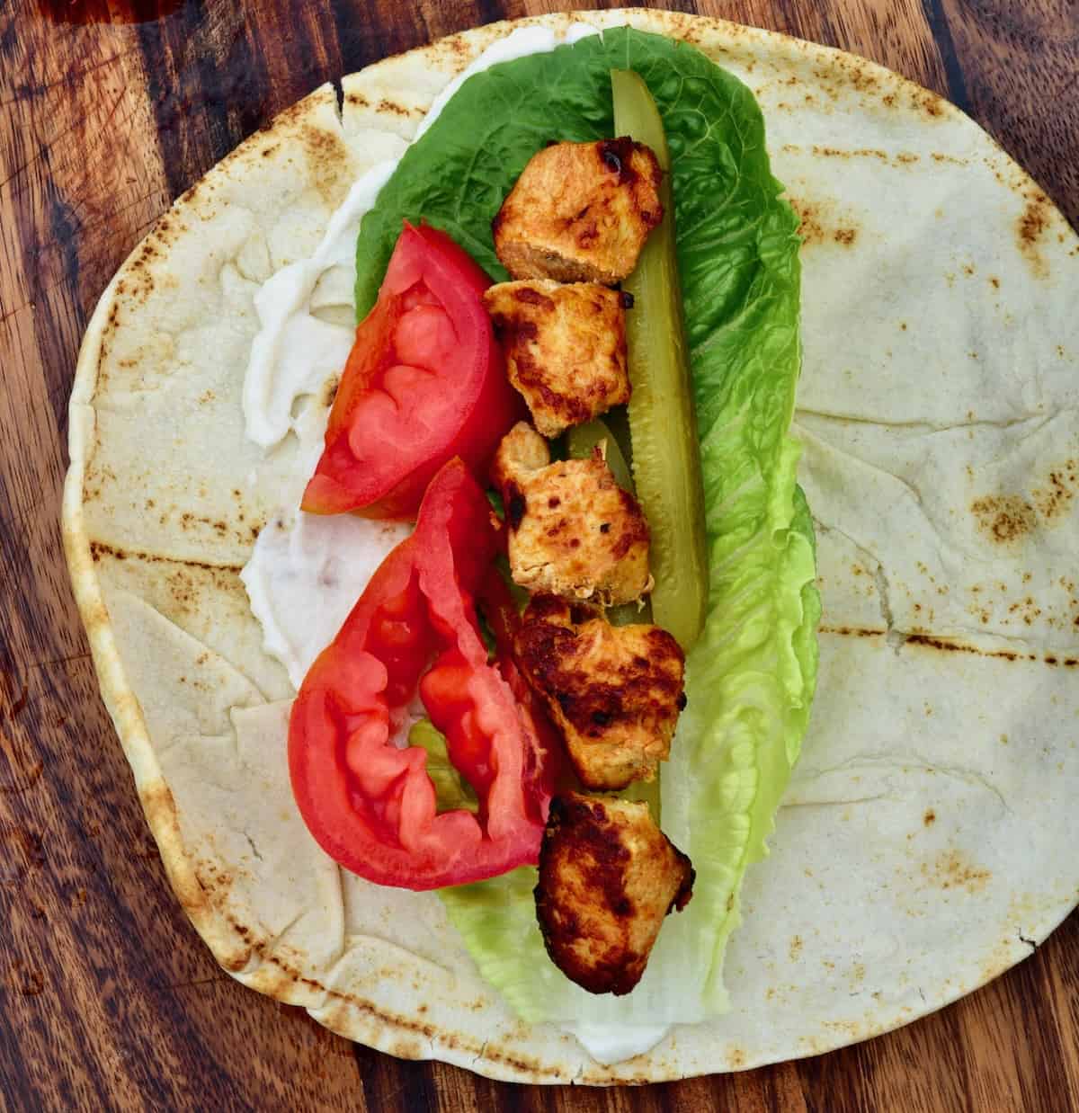 Homemade chicken shish tawook with tomatoes and lettuce over pita