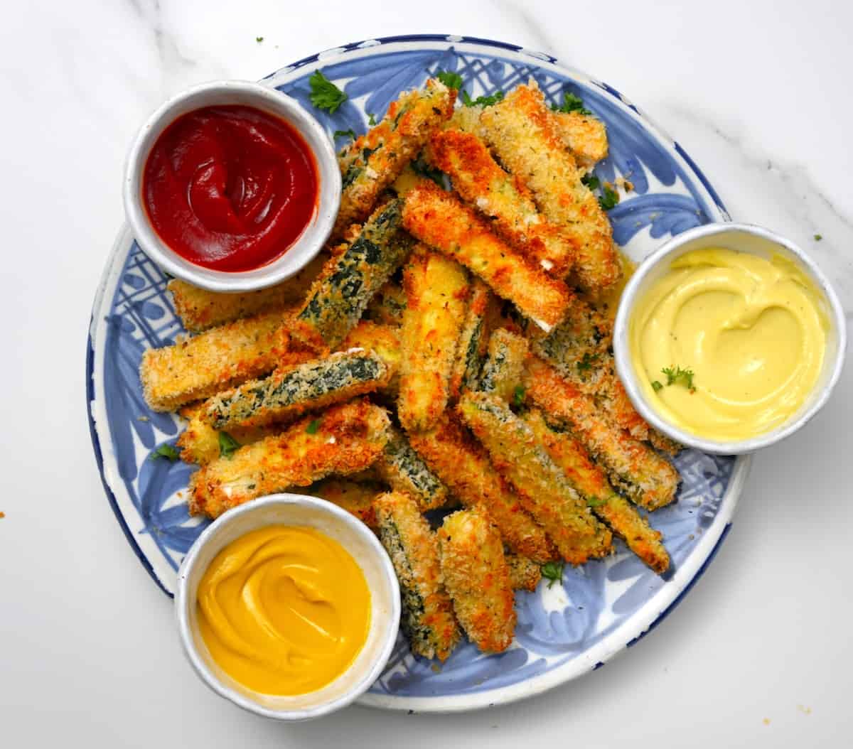 Air fryer zucchini with ketchup, mayo and mustard in little bowls
