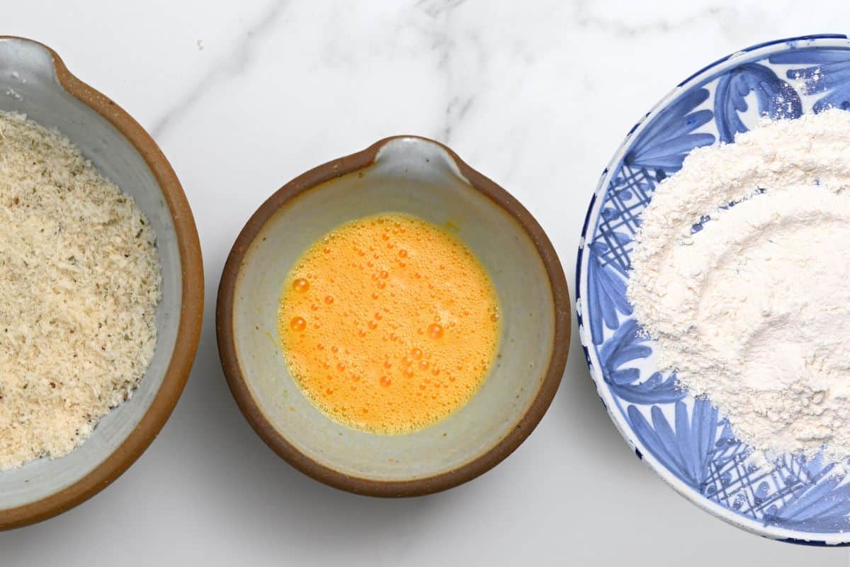Three bowls with flour, whisked eggs, and breadcrumbs