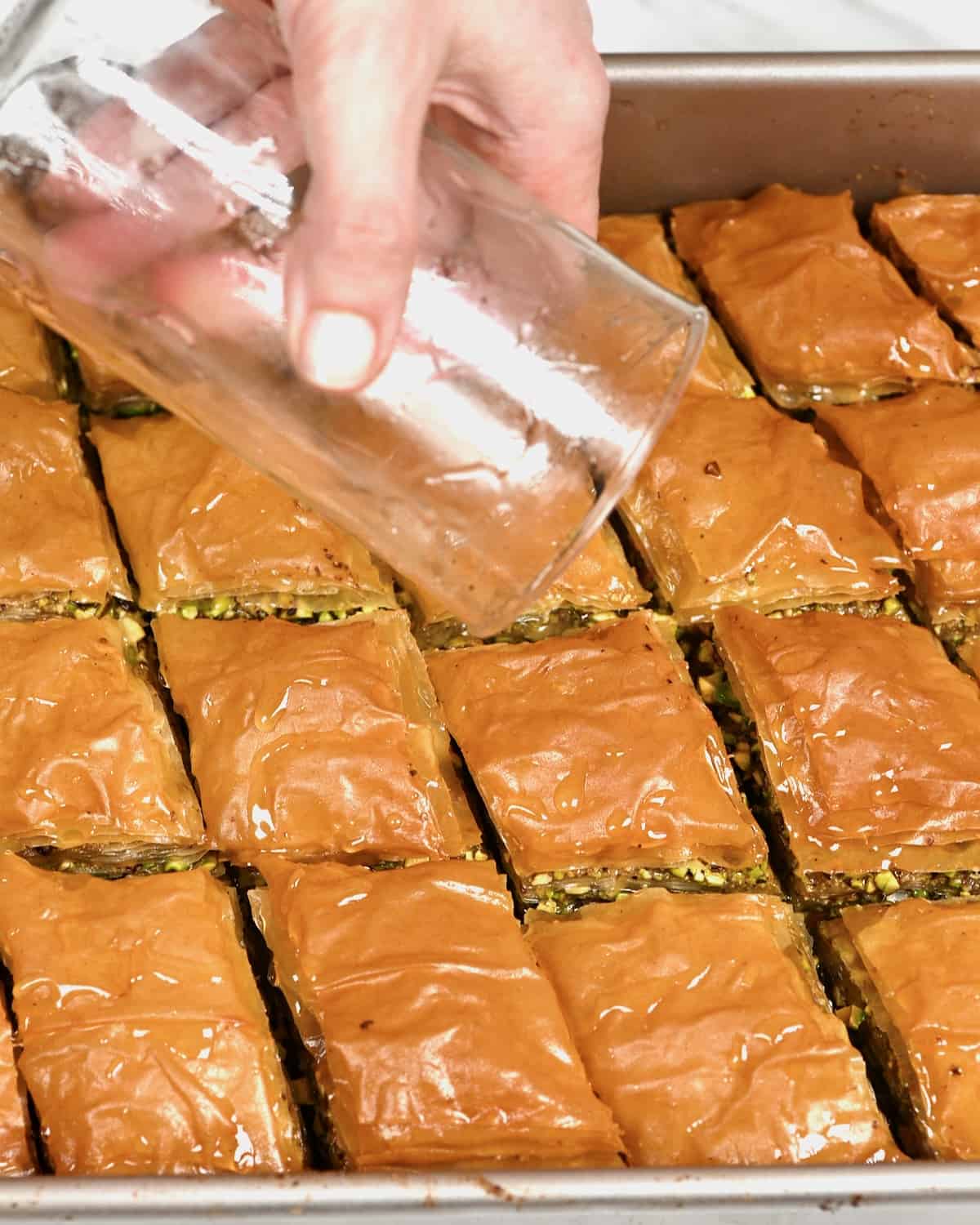 Pouring cold syrup over hot baklava