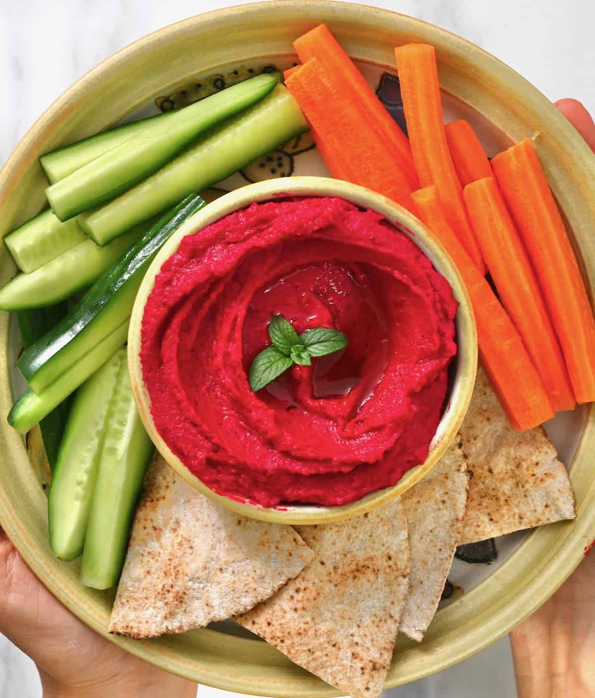 Homemade roasted beet hummus served with carrot and cucumber sticks and pita chips