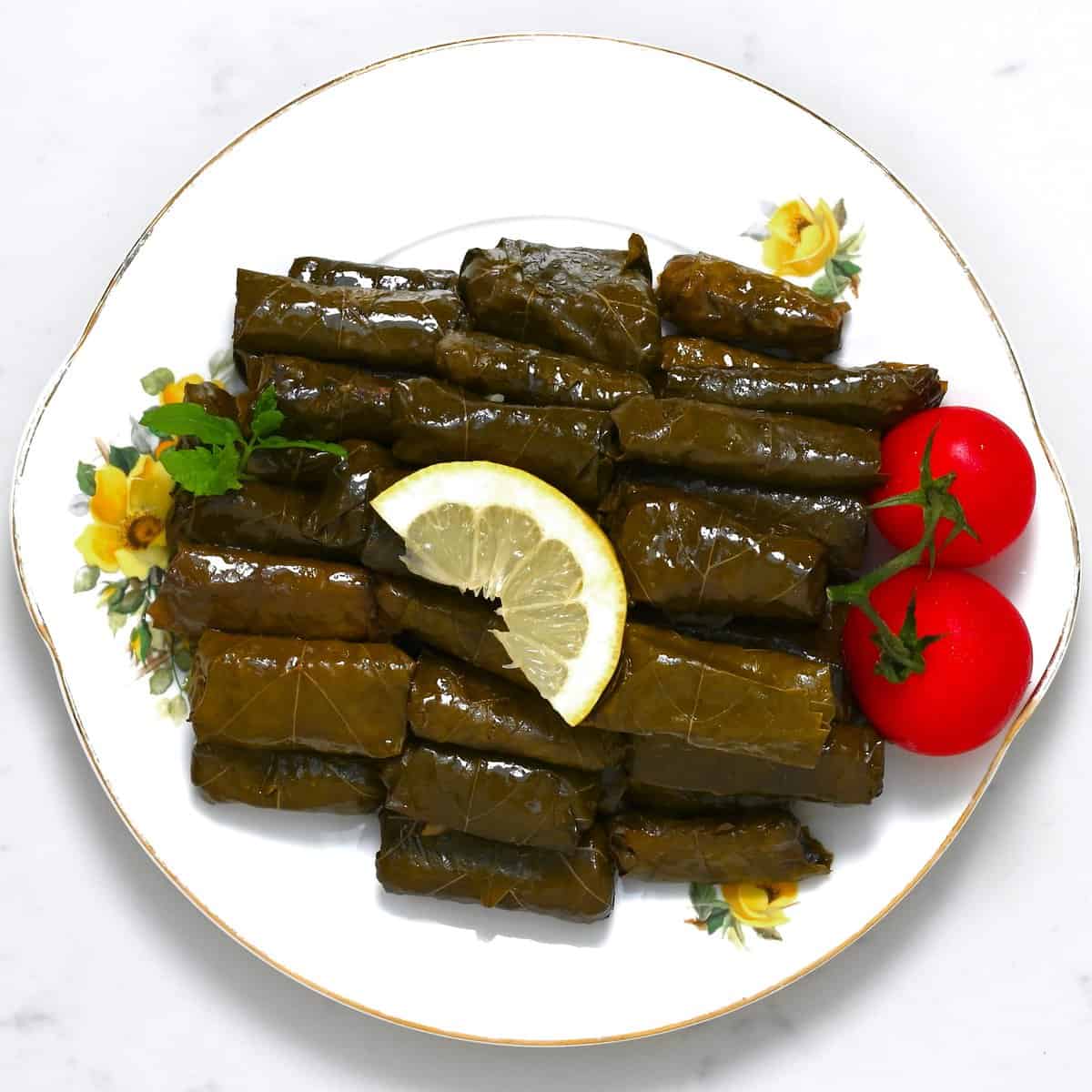 A serving of dolmas with tomatoes and lemon slice