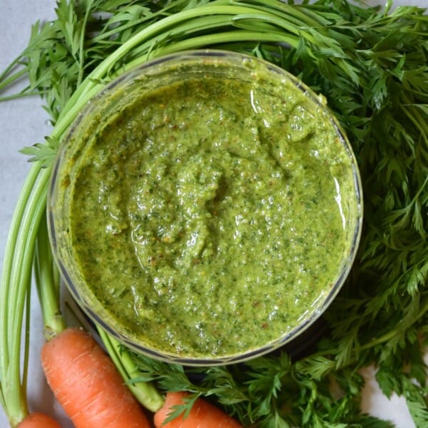 Carrot top pesto in a bowl with carrot leaves around it