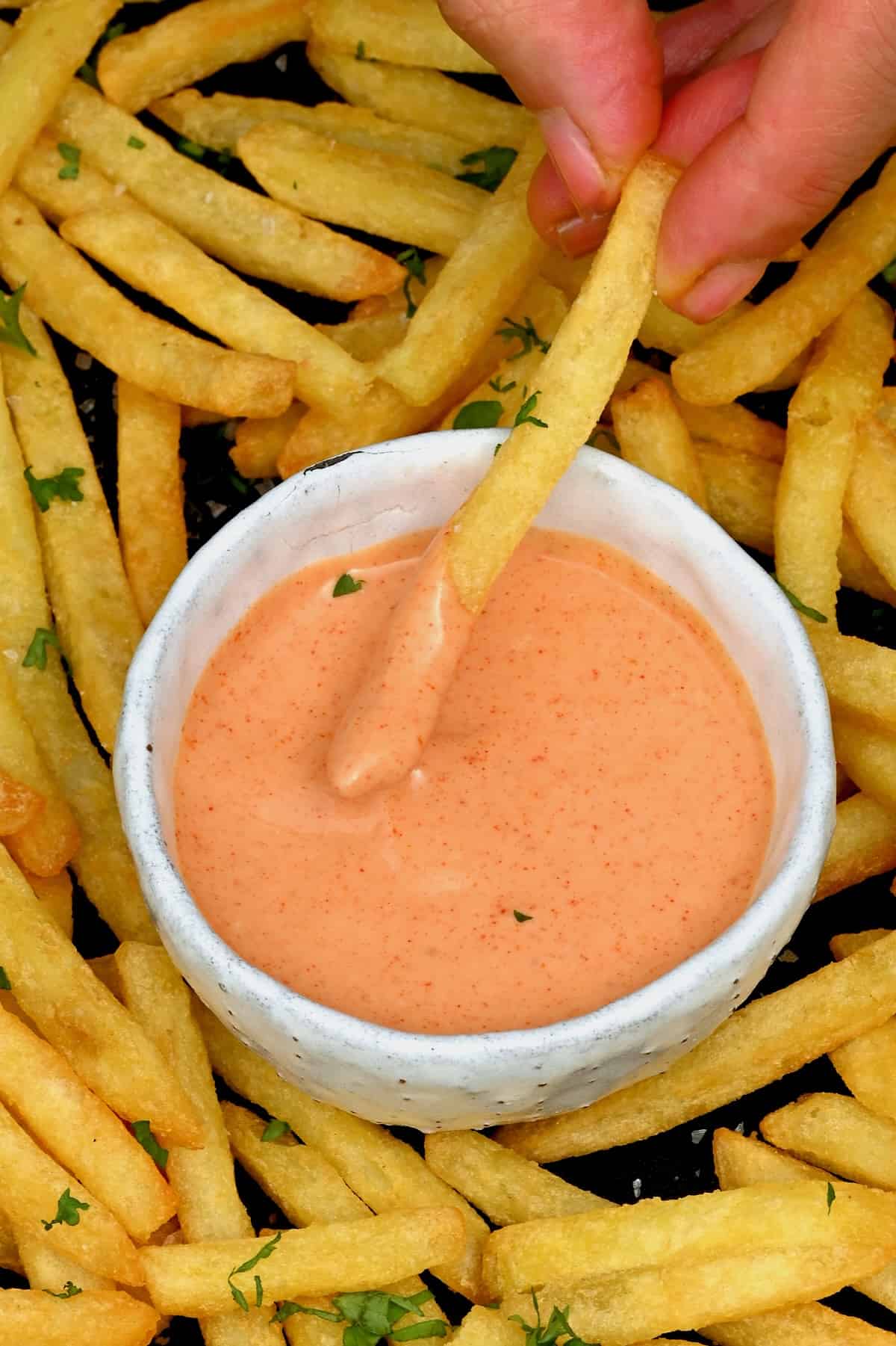 A French fry being dipped in fry sauce
