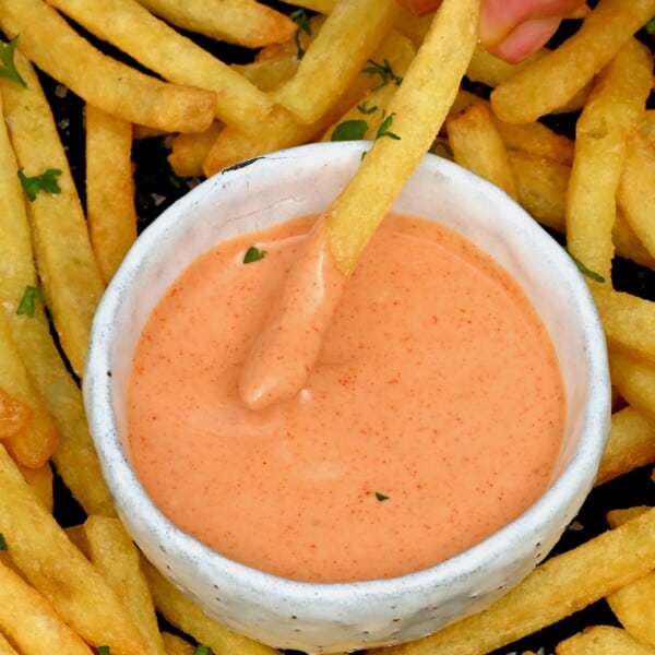 A French fry being dipped in fry sauce