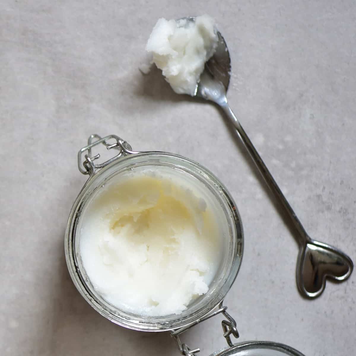 A jar with homemade coconut oil and a spoon next to it