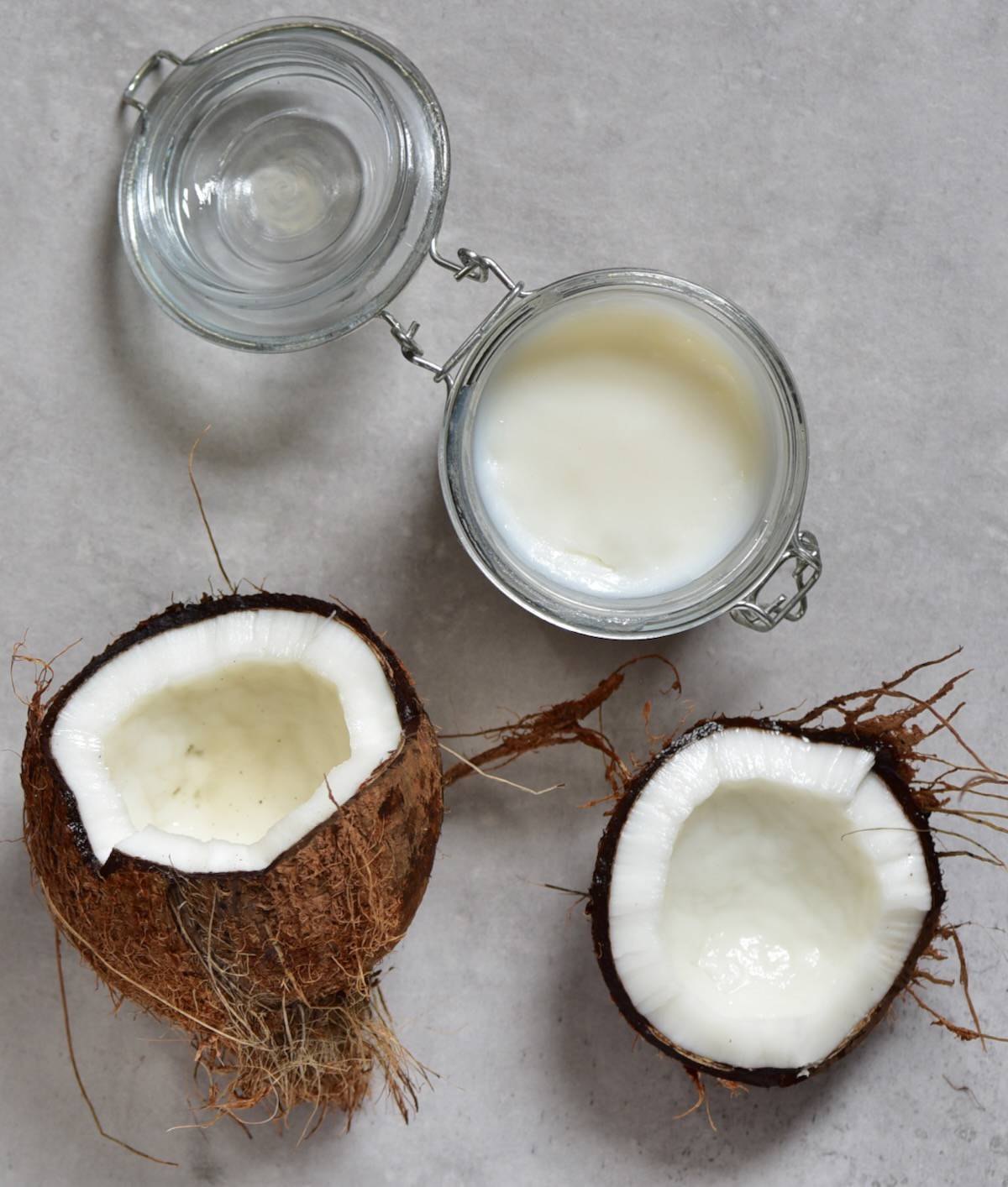 Homemade coconut oil in a small jar and an opened coconut next to it