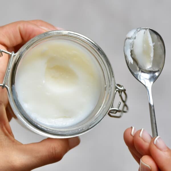 Homemade coconut oil in a small jar and a spoon