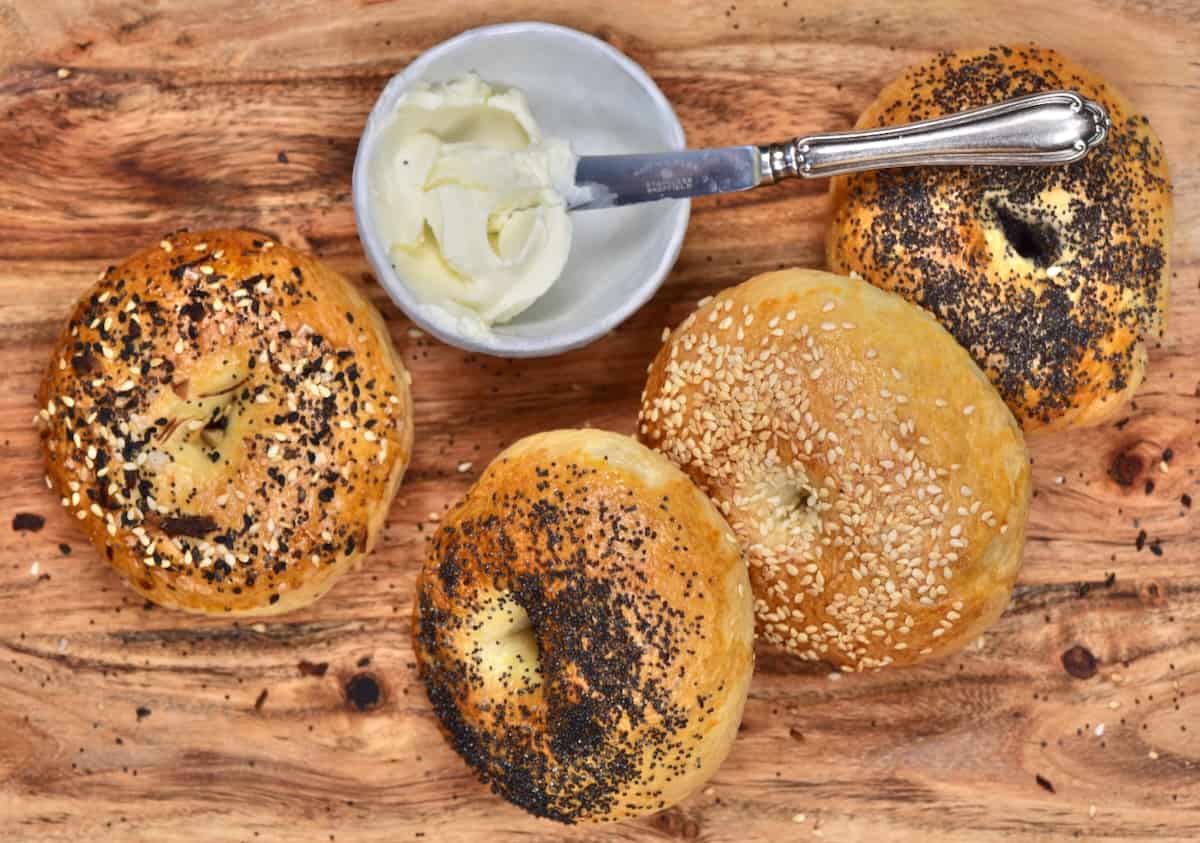 Four homemade bagels and a small bowl with cream cheese