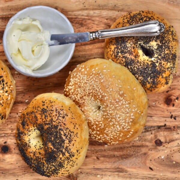 Three homemade bagels and a small bowl with cream cheese