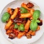 A serving of Pasta Alla Norma topped with fresh basil leaves - 25