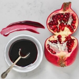 A small bowl with homemade pomegranate molasses and an opened pomegranate