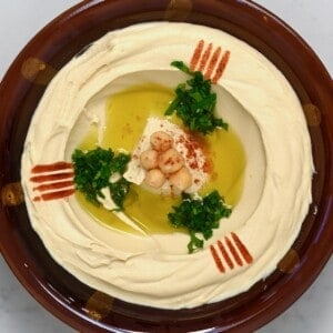 A bowl with homemade hummus topped with olive oil, paprika, chickpeas, and parsley