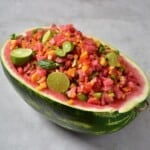 Watermelon salsa served in a watermelon bowl topped with lime halves
