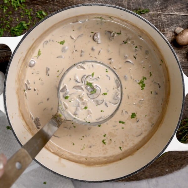A ladleful of homemade mushroom soup over a large pot