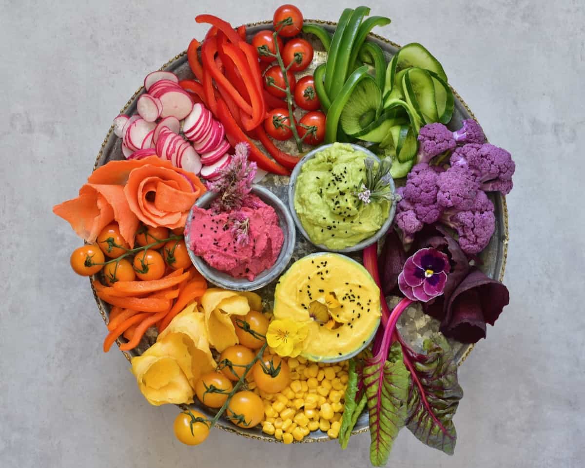 Veggie platter with differently colored hummus in small bowls