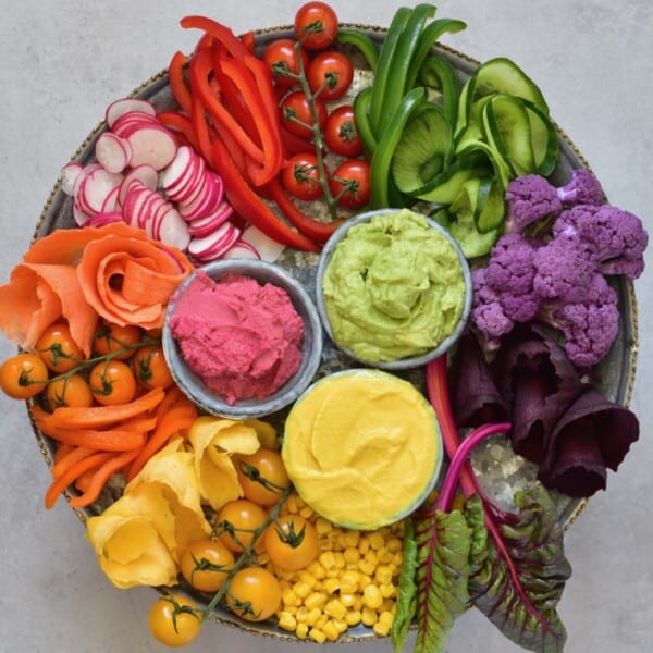 Veggie platter with differently colored hummus in small bowls