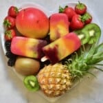 A heart-shape plate filled with berries, kiwi, and pineapple topped with homemade fruit popsicles - 20