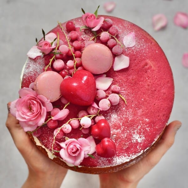 Red velvet cake decorated with red berries and heart-shaped chocolates