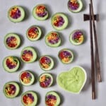 Slices of cucumber sushi stuffed with vegetables with avocado dipping sauce and chopsticks - 16