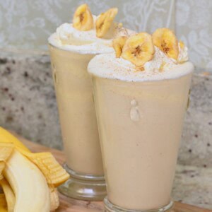 Two glasses with homemade banana milkshake topped with banana chips