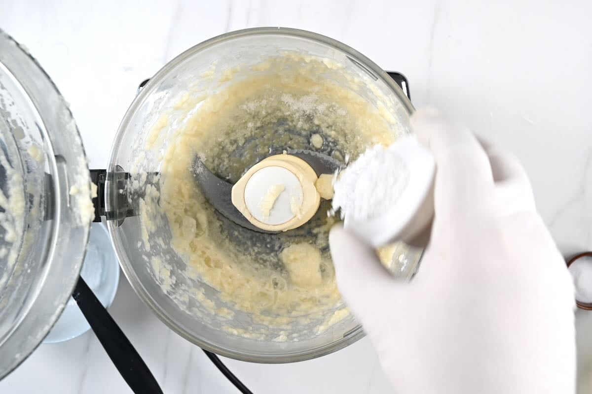Adding salt to blended garlic.
