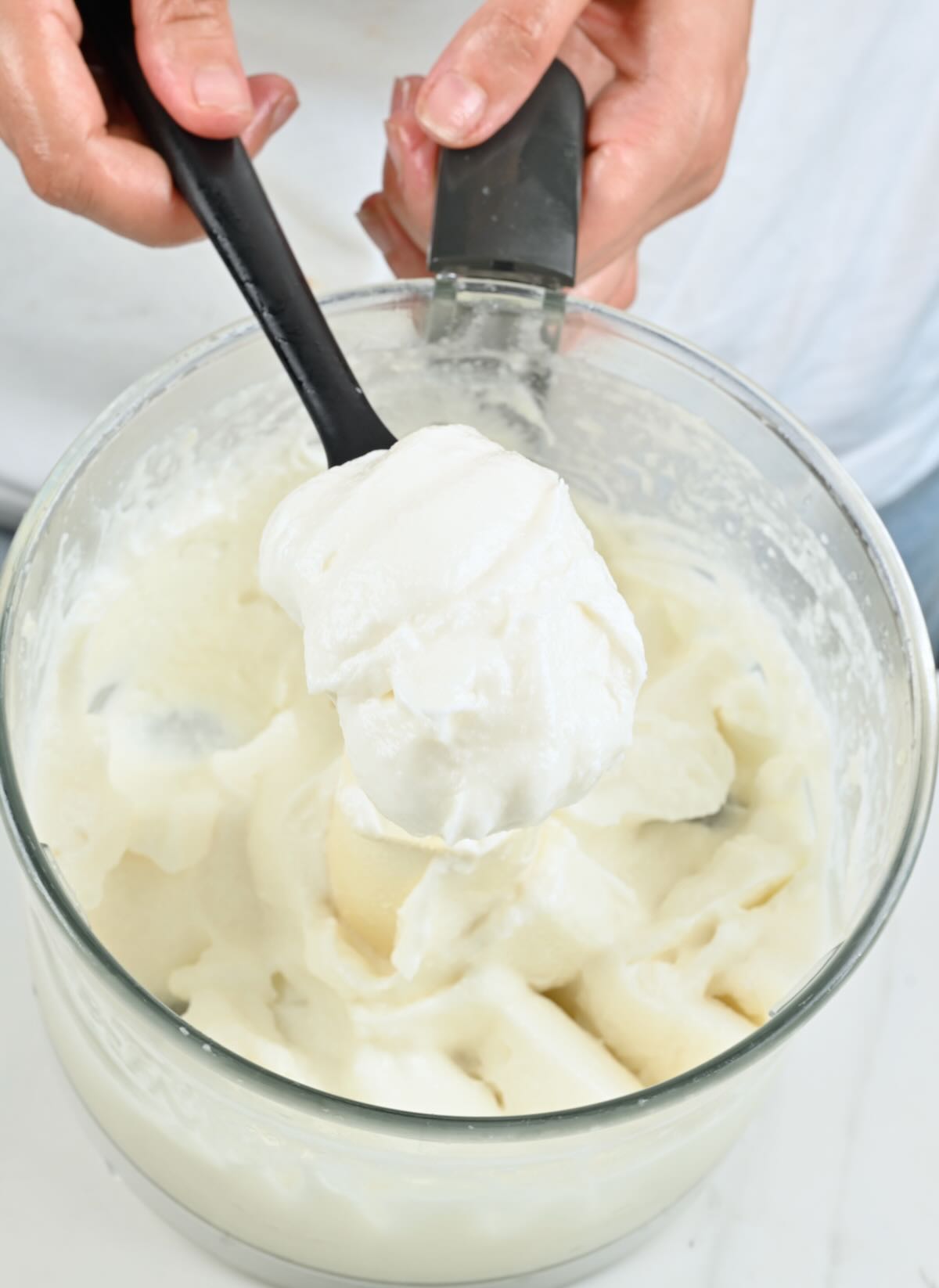 A spoonful of freshly made toum over a food processor.